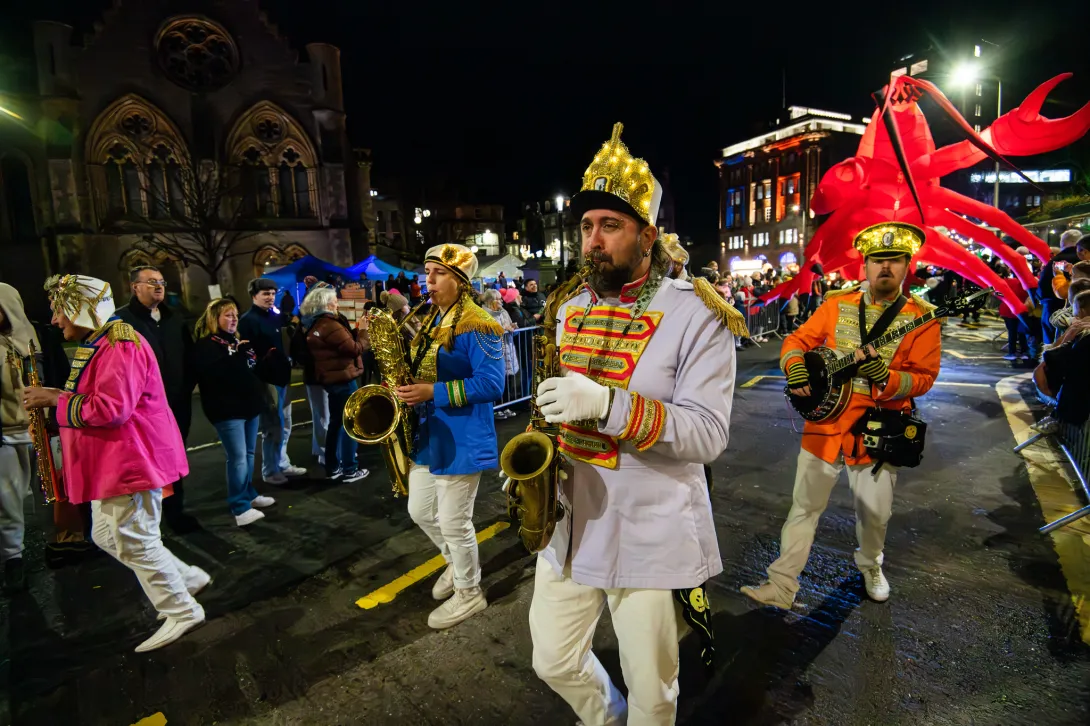 Colourful brass band parading through a crowded street